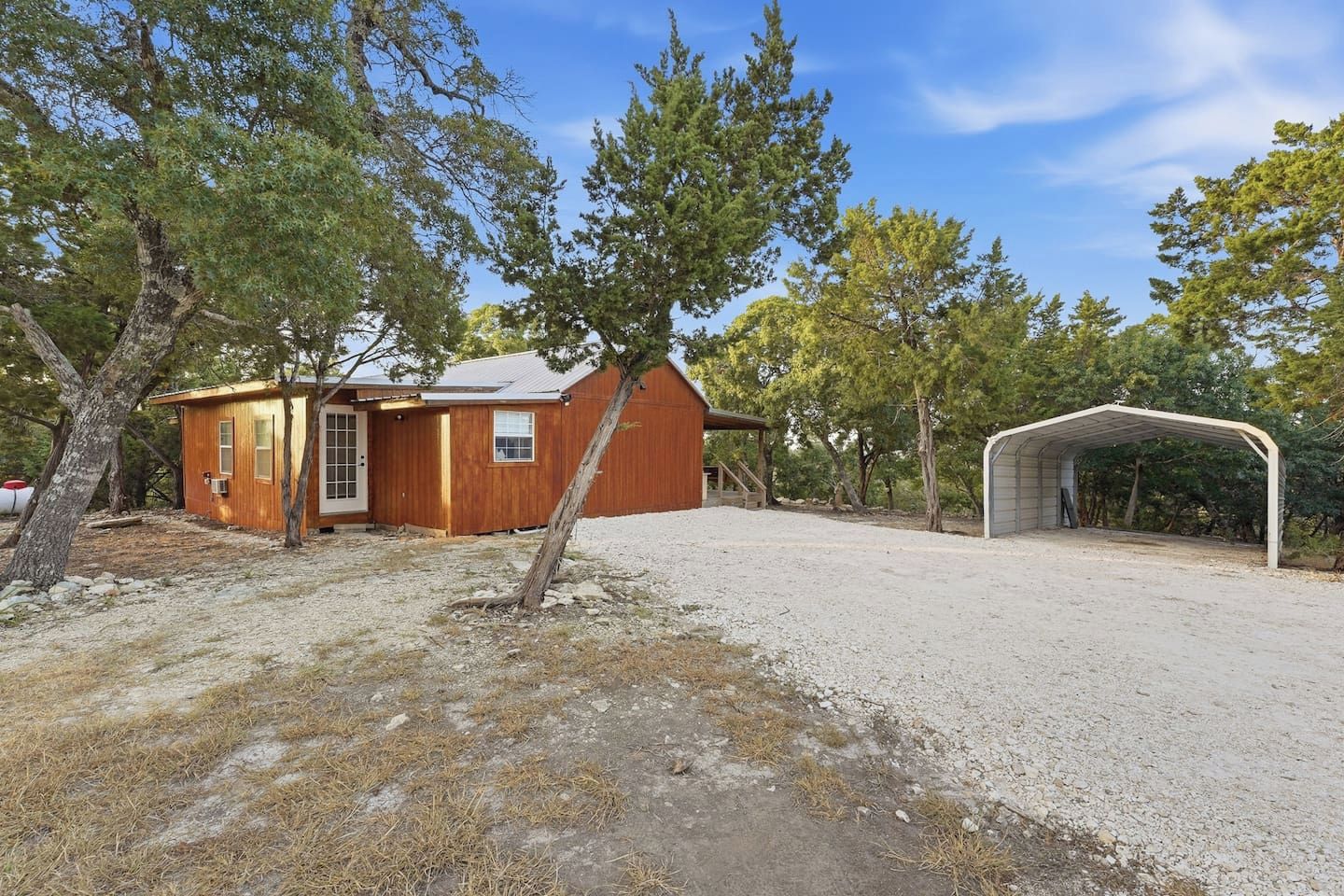 Una baita in legno con un garage e un portico coperto, immersa tra gli alberi.