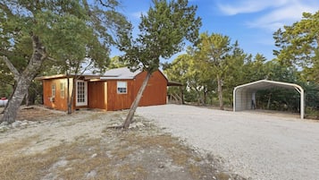 Una baita in legno con un garage e un portico coperto, immersa tra gli alberi.