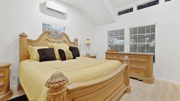 A bedroom with a large bed, a dresser, a nightstand, and a window with blinds.