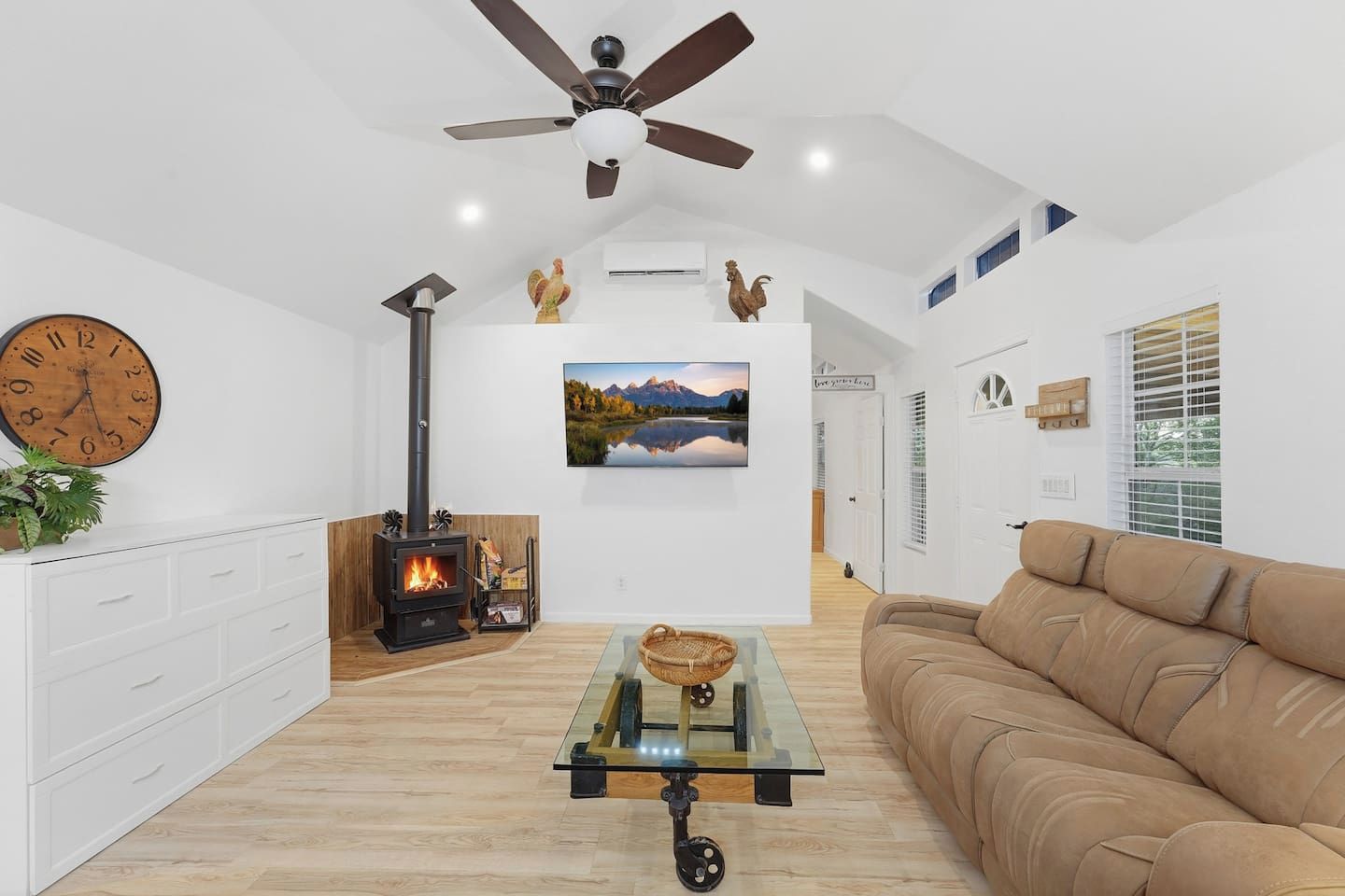 A modern living room with a fireplace, a sofa, a coffee table, and a clock on the wall.