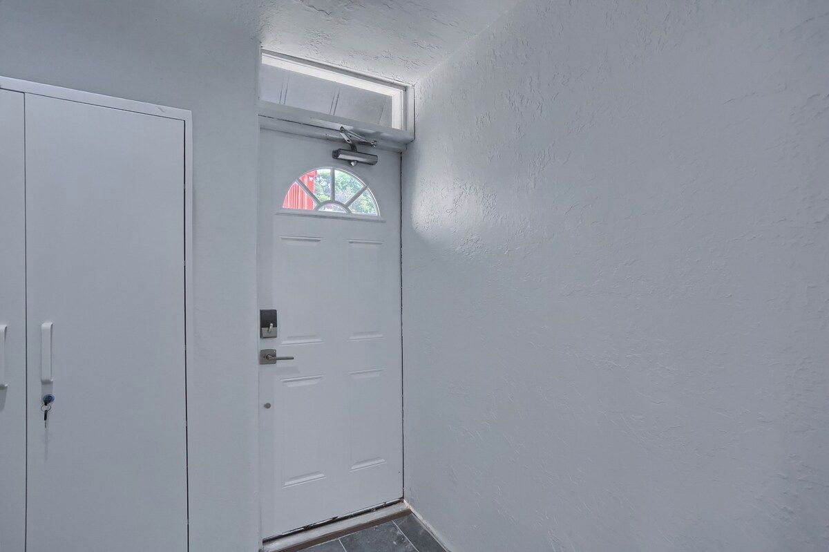A white door with a window, a doorbell, and a small window above it.