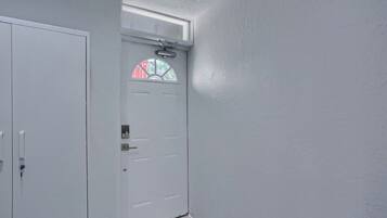 A white door with a window, a doorbell, and a small window above it.