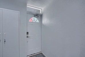 Une porte blanche avec une fenêtre, un interphone et une petite fenêtre au-dessus.