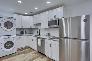 A modern kitchen with stainless steel appliances, white cabinetry, and a granite countertop. - Pittsburgh, Millvale 3 Cozy Studio Apartment with Parking (Pittsburgh)
