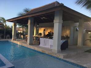 A covered outdoor dining area with a pool, tables, chairs, and a grill. - Paradise in Puerto Plata! Spacious villa with private pool and much more!!!! (Santo Domingo Este)