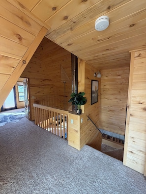 En interiör med träpanel, en trappa, en ventil i taket och en krukväxt.