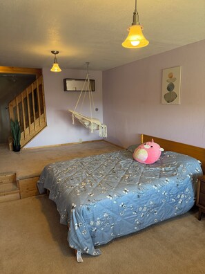 A bedroom with a bed, a hanging chair, a staircase, and a wall-mounted air conditioner. - Mountain top A-frame with hot tub and Sauna (Fairplay)