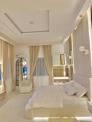 Quarto moderno com uma cama grande, uma penteadeira com espelho e um lustre.