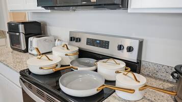 A kitchen with a stove, pots, pans, and a toaster.