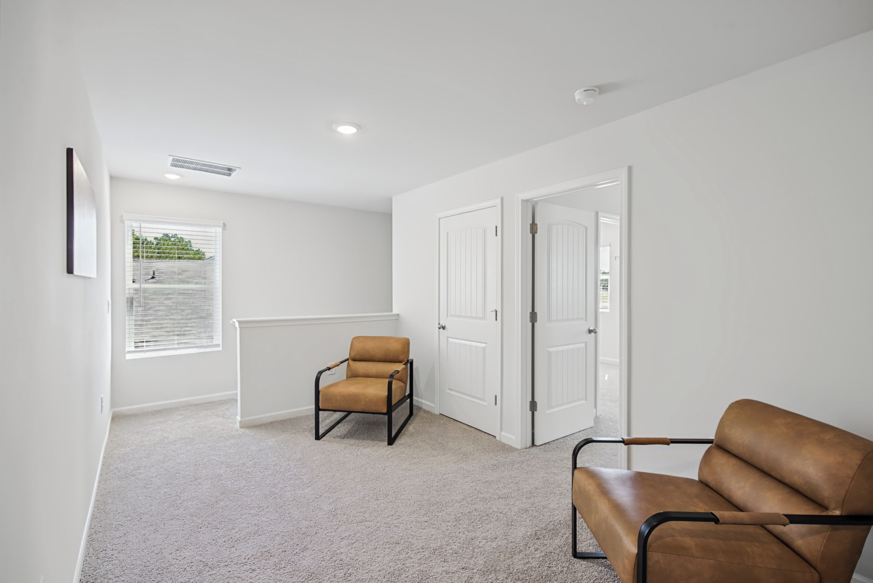 A room with a brown leather chair, white walls, a radiator, and a window with blinds.