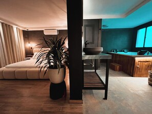 A modern living room with a large potted plant, a sofa, and a dining area with a wooden table and chairs. - Sense 2 Jacuzzi Suite in Poblado (Medellín)