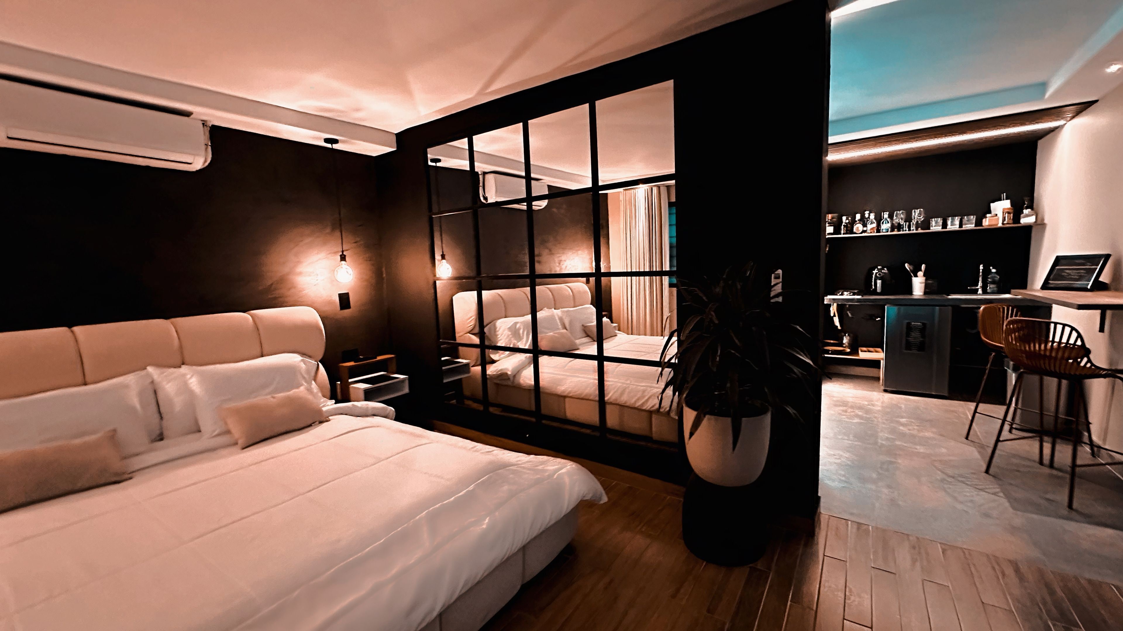 A modern bedroom with a large bed, a desk, and a view through a glass partition.