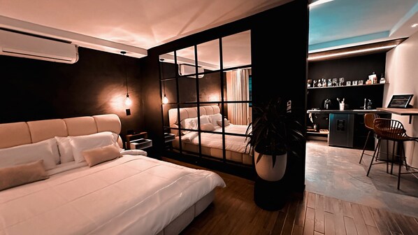Een moderne slaapkamer met een groot bed, een bureau en uitzicht door een glazen scheiding.