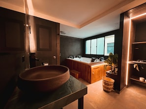 A modern bathroom with a large bathtub, a wooden vanity, and a window providing natural light. - Sense 2 Jacuzzi Suite in Poblado (Medellín)