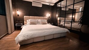 Een moderne slaapkamer met een groot bed, nachtkastjes en een spiegelwand.