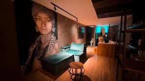 Ein modernes Interieur mit einer Couch, einem runden Holzhocker und einem großen Wandbild.