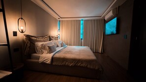 Un dormitorio con cama, cortinas, televisor montado en la pared y lámpara en el techo.