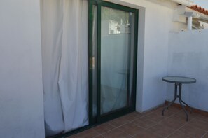 A room with a sliding glass door, a small round table, and a tiled floor. - Town House in the centre of Alte. Family or group retreat to secret of Algarve (Alte)