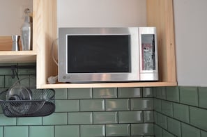 A microwave oven on a wooden shelf above a tiled backsplash. - Town House in the centre of Alte. Family or group retreat to secret of Algarve (Alte)