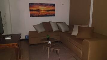 A living room with a brown sofa, a coffee table, and a painting of a sunset.