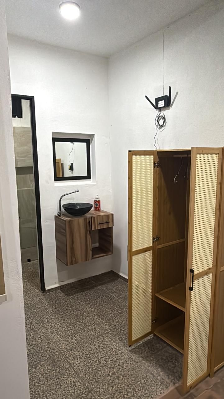 A bathroom with a wooden vanity, a mirror, and a towel rack.