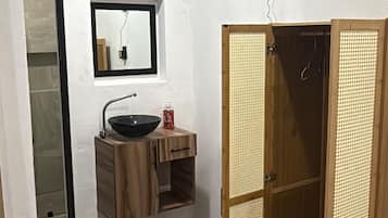 A bathroom with a wooden vanity, a mirror, and a towel rack.
