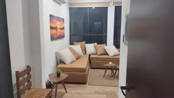 Ein Wohnzimmer mit einer Sofagarnitur, einem kleinen Tisch mit einer Pflanze und einem Fenster mit Blick.