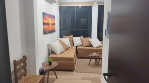 Un salon comprenant un canapé, une petite table avec une plante et une fenêtre donnant sur un beau paysage.