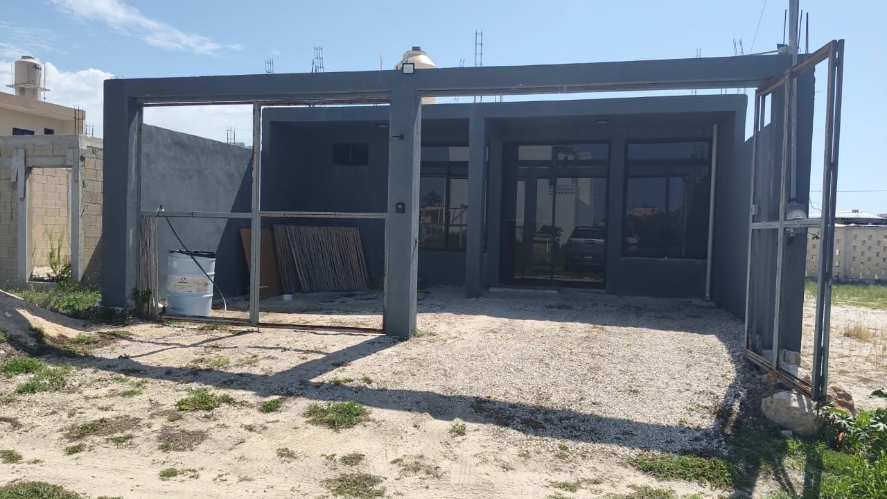 Um canteiro de obras com estrutura metálica, chão de brita e materiais de construção.