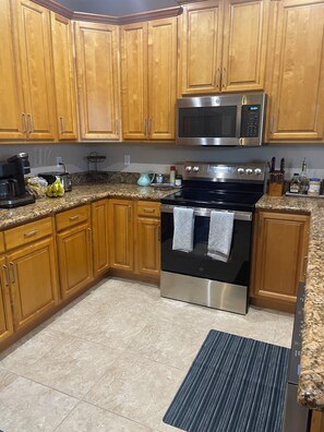 A kitchen with wooden cabinets, a stainless steel oven, a microwave, and granite countertops. - Snook Shack - 3 Bedroom/2 Bath Condo Located in Historic Everglades City (Everglades City)