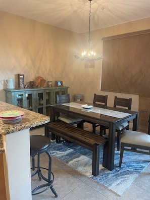 A dining area with a wooden table, benches, and a chandelier. - Snook Shack - 3 Bedroom/2 Bath Condo Located in Historic Everglades City (Everglades City)