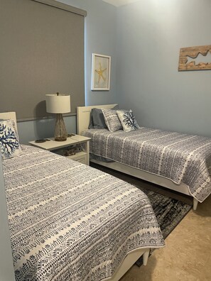 A bedroom with two beds, a nightstand, a lamp, and a starfish decoration on the wall. - Snook Shack - 3 Bedroom/2 Bath Condo Located in Historic Everglades City (Everglades City)
