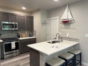 A modern kitchen with a built-in microwave, oven, and stainless steel range hood. - Oak Street Retreat (Florence)