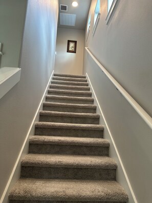 A carpeted staircase with a handrail, leading to a landing with a framed picture. - Oak Street Retreat (Florence)