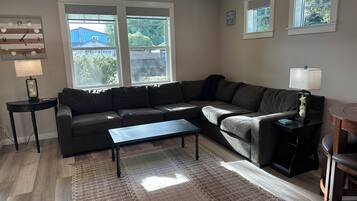 A living room with a sectional sofa, a coffee table, a rug, and a side table with a lamp.