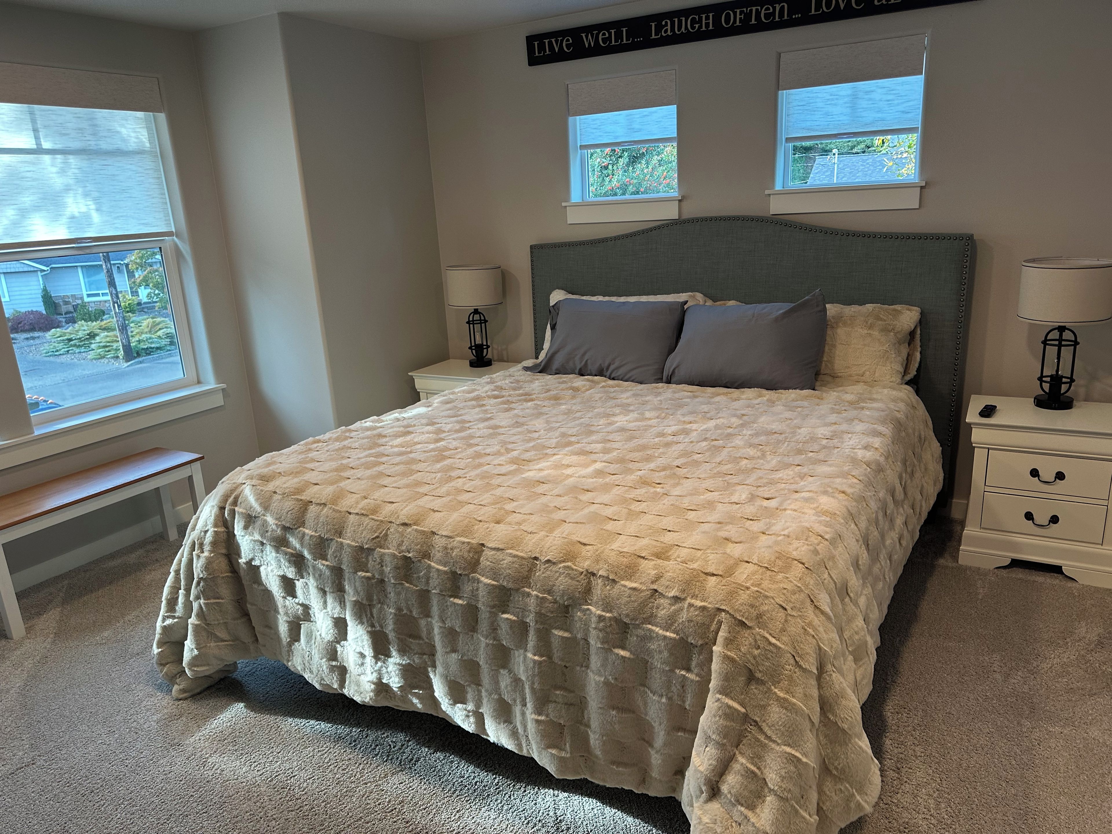 A bedroom with a bed, two bedside tables, a bench, and a window.