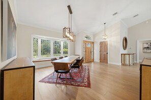 A spacious dining area with a long wooden table, multiple chairs, and a patterned rug.