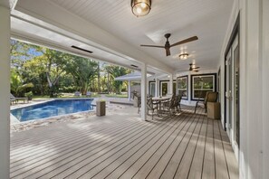 Ein überdachter Außenbereich mit Pool, Sitzgelegenheiten und Deckenventilatoren.