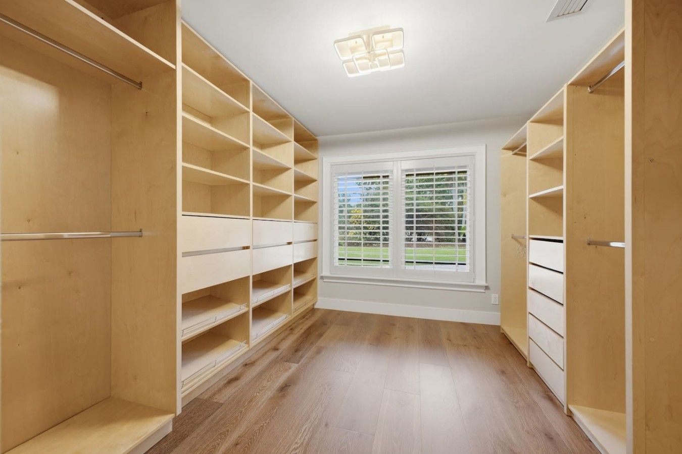 A walk-in closet with open shelves and a window with blinds.