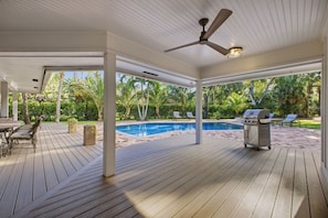 A covered outdoor area with a pool, wooden deck, ceiling fan, and grilling station. - Wellington Equestrian Escape | Ranch w/ Pool (Wellington)