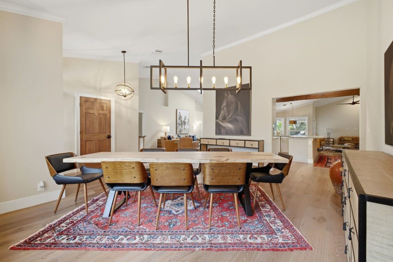 A modern dining area with a large table, chairs, and a hanging light fixture.