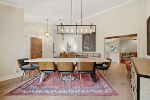 A modern dining area with a large table, chairs, and a hanging light fixture. - Wellington Equestrian Escape | Ranch w/ Pool (Wellington)