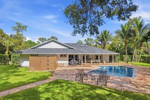 A residential property with a swimming pool, a covered patio, and a fenced backyard.