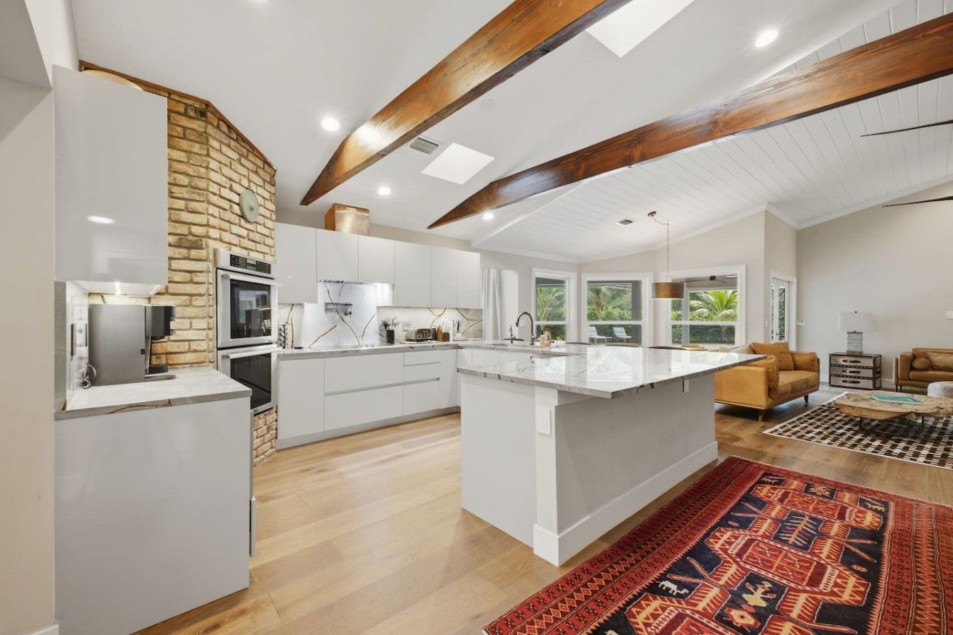 A spacious kitchen with a central island, white cabinetry, and a brick accent wall.