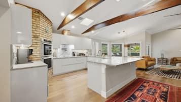 A spacious kitchen with a central island, white cabinetry, and a brick accent wall.