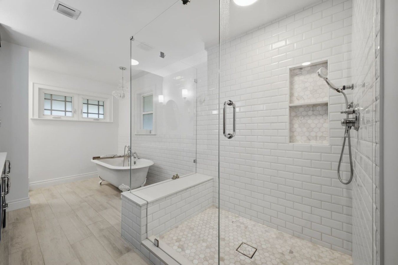 A modern bathroom with a glass-enclosed shower, a freestanding bathtub, and a vanity with a mirror.