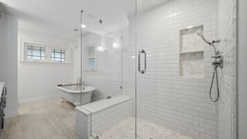 A modern bathroom with a glass-enclosed shower, a freestanding bathtub, and a vanity with a mirror.