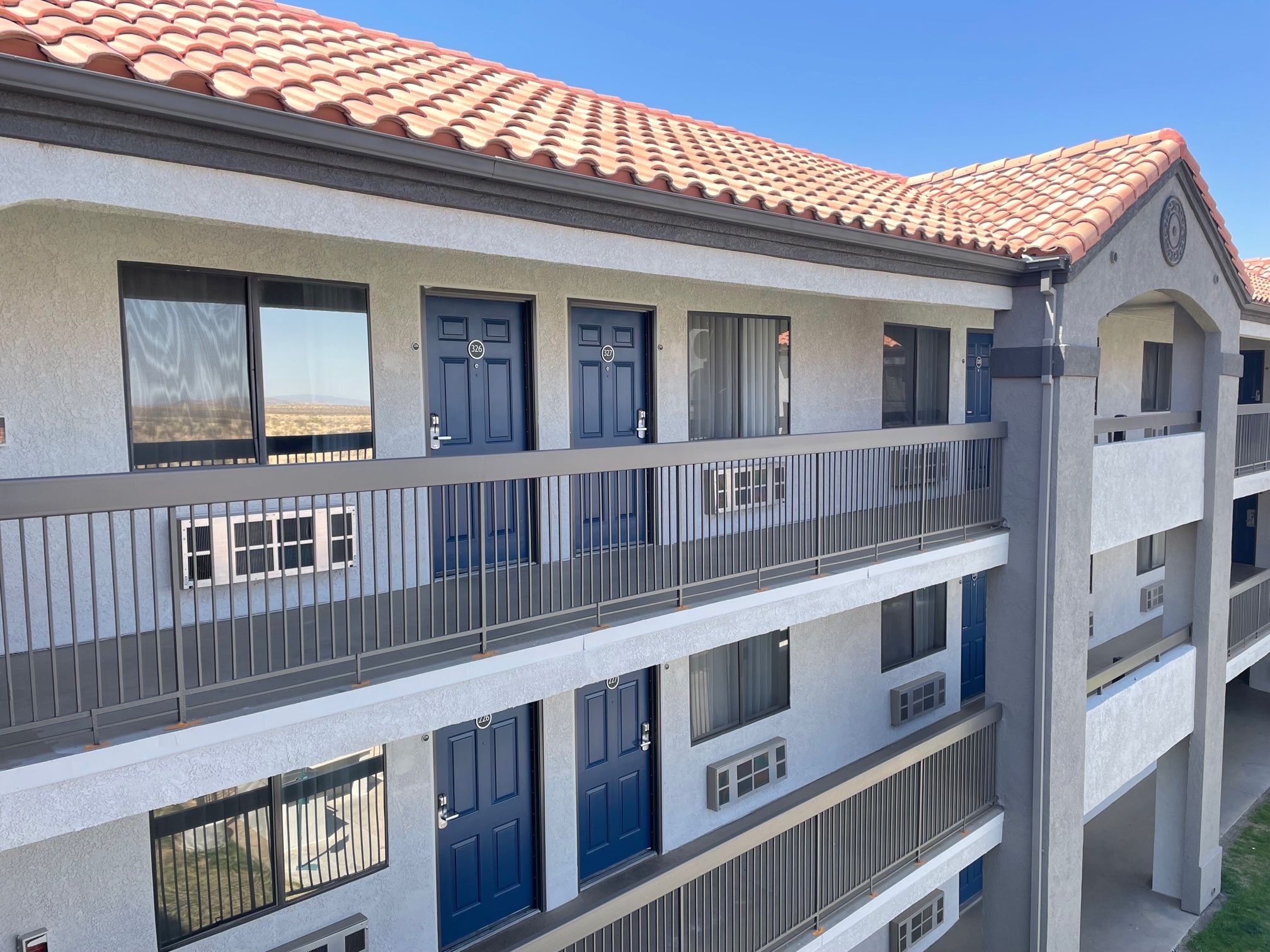 A multi-story building with balconies, large windows, and a tiled roof.