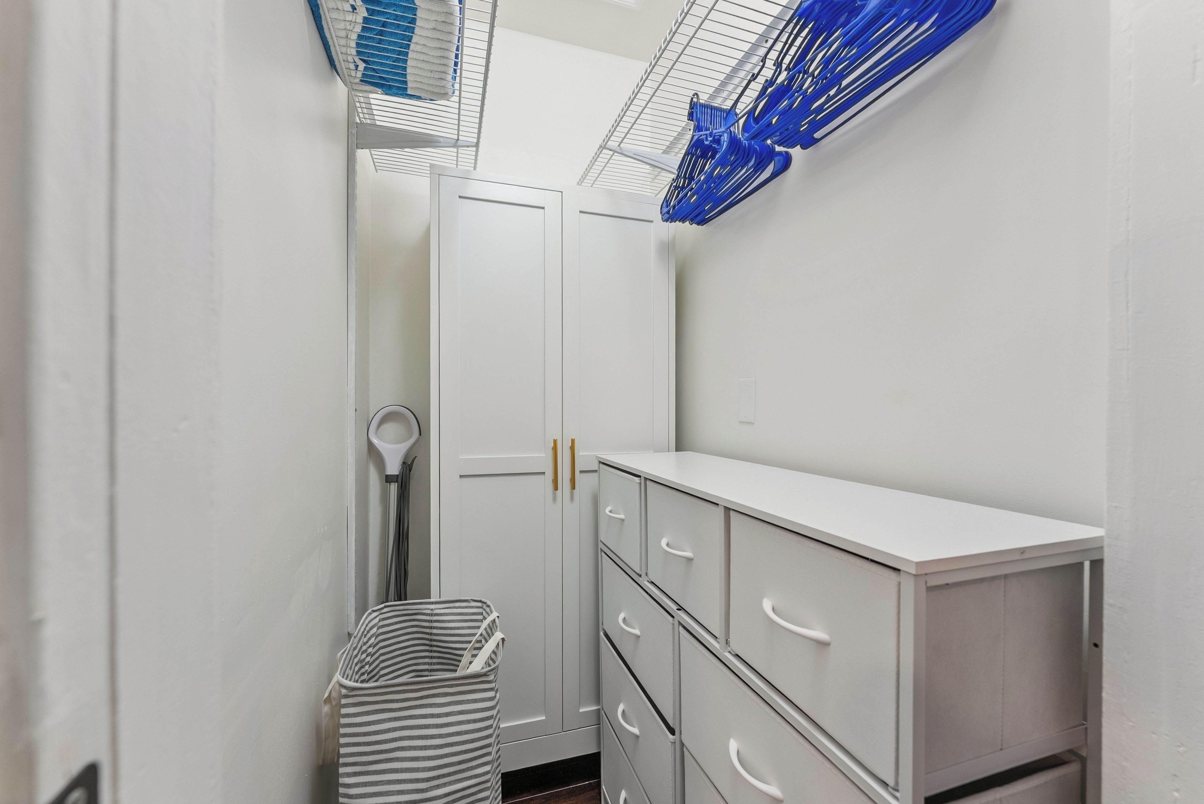 A narrow hallway with white cabinets and a striped trash bin.