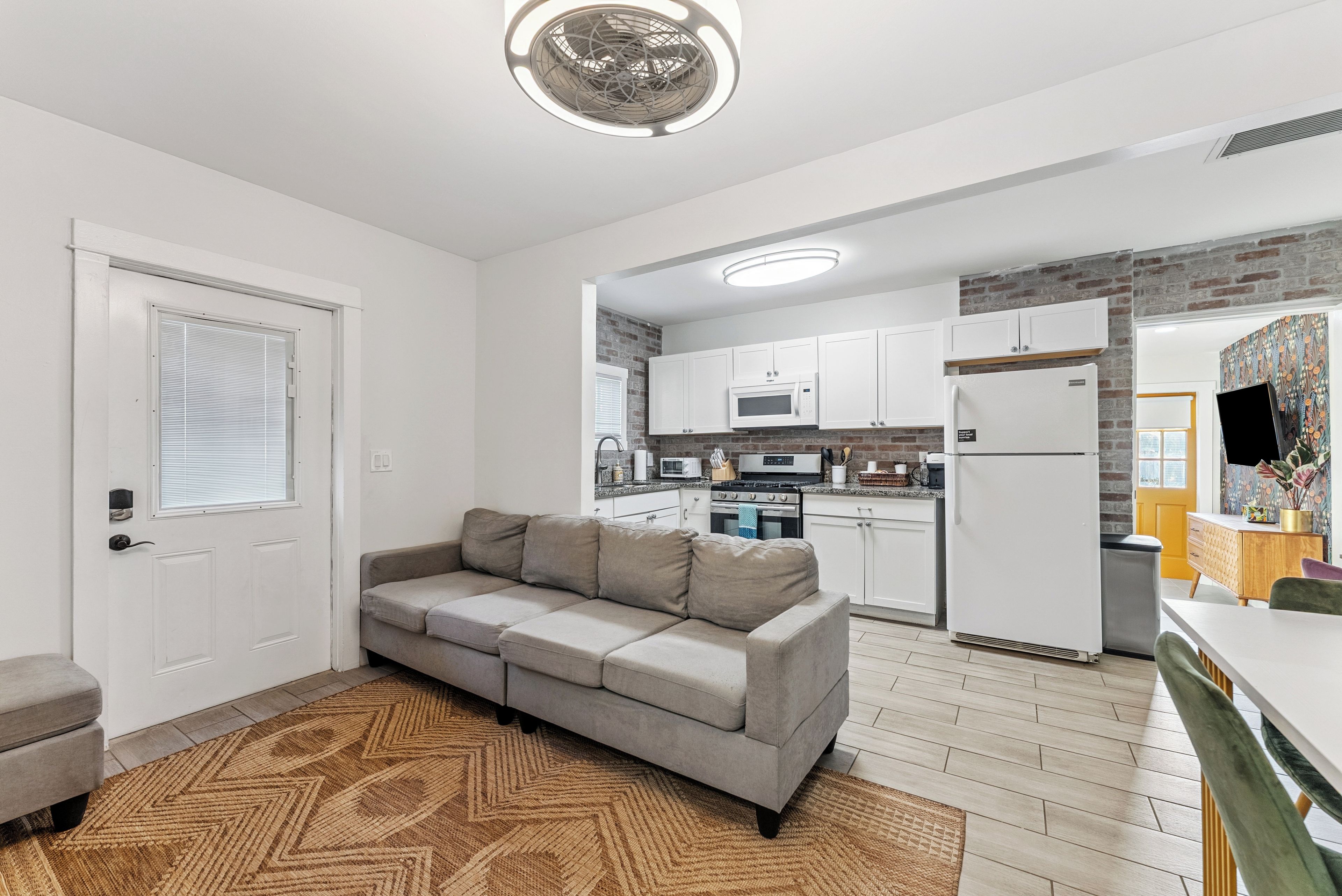 A compact living space with a kitchenette, a sofa, and a patterned rug.